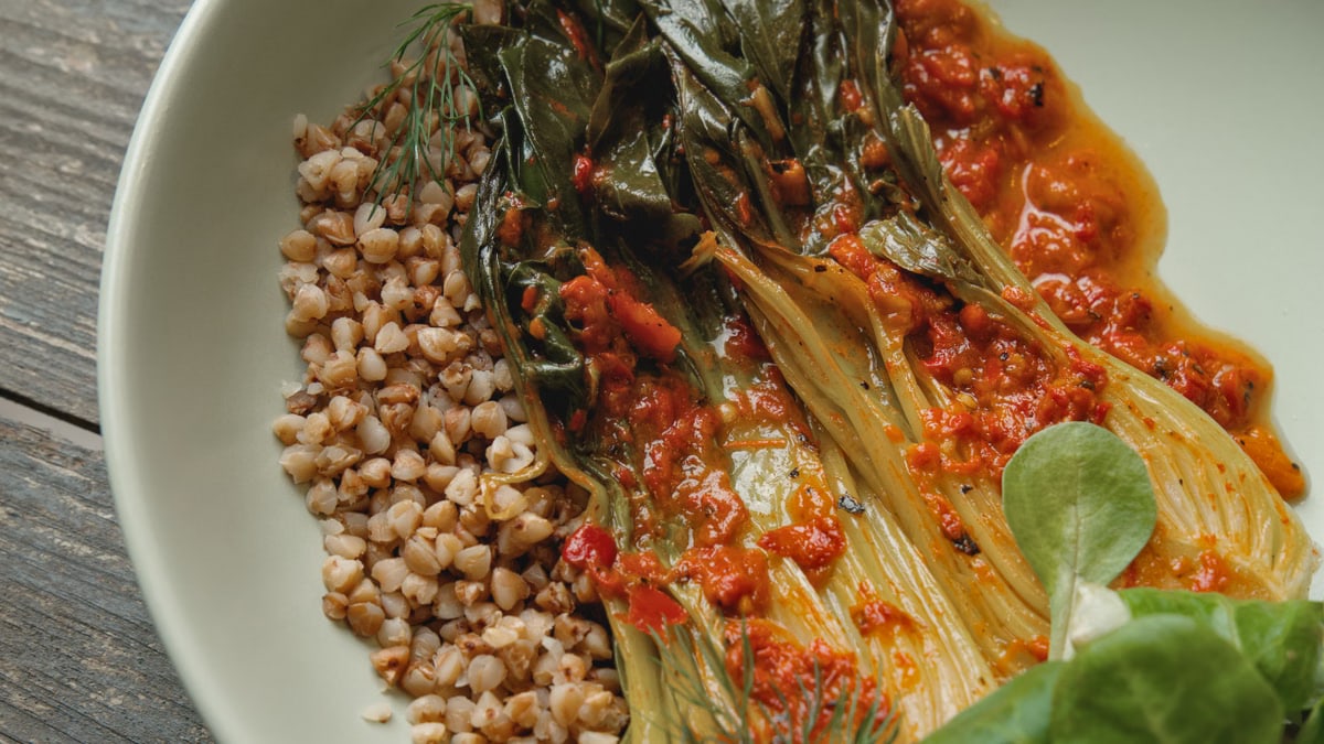 Appetizing dish of grains, greens, and spicy kimchi on rustic tableware.